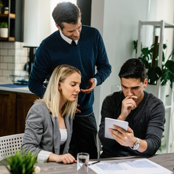 Young couple feeling uncertain while using digital tablet on a meeting with their insurance agent at home.